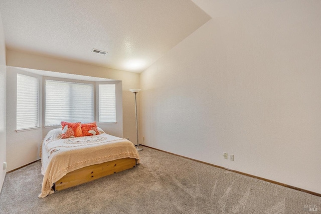 bedroom with lofted ceiling, a textured ceiling, carpet flooring, visible vents, and baseboards