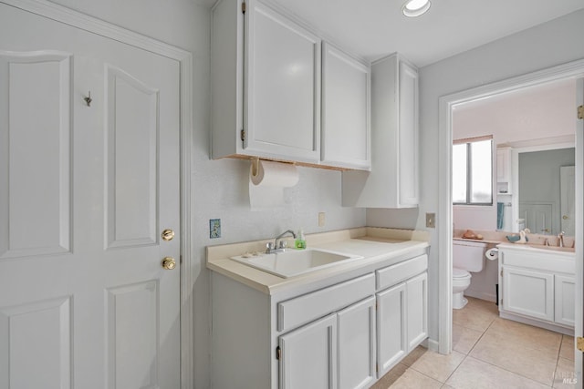 kitchen featuring light tile patterned flooring, white cabinets, a sink, and light countertops