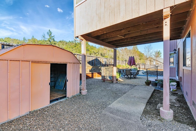 view of yard with an outbuilding, outdoor dining area, a patio, a storage shed, and a fenced backyard