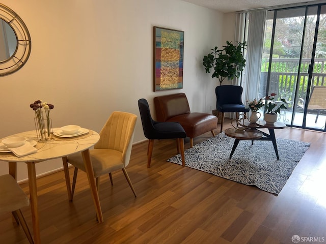 living area with a wall of windows, baseboards, and wood finished floors