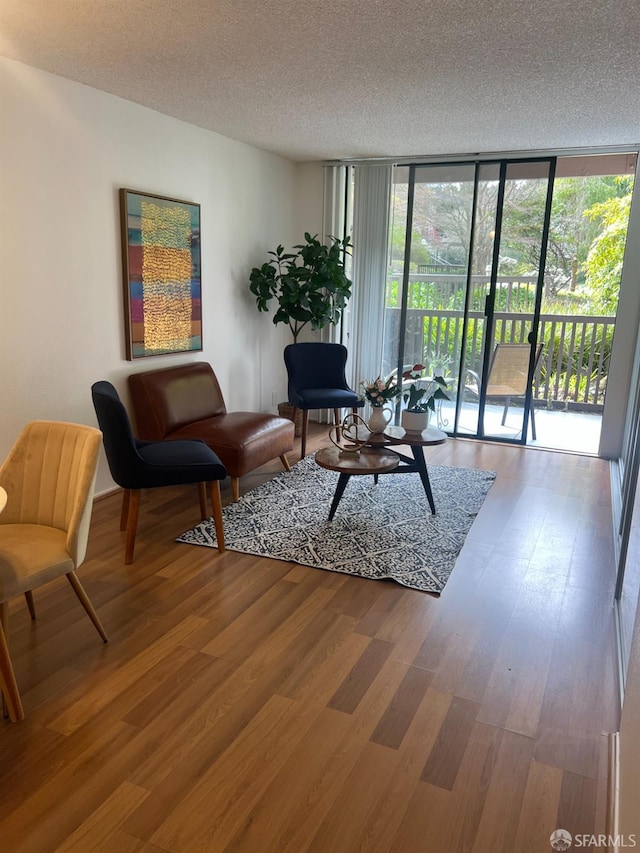 living room with a textured ceiling, wood finished floors, and floor to ceiling windows