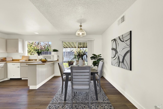 dining space with dark wood-style floors, a textured ceiling, visible vents, and baseboards