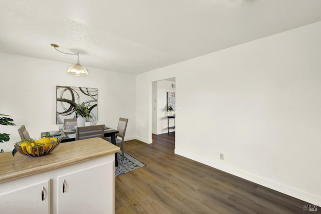 dining space featuring dark wood-style floors, a textured ceiling, and baseboards