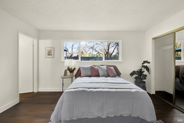 bedroom with a textured ceiling, dark wood-type flooring, multiple windows, and a closet