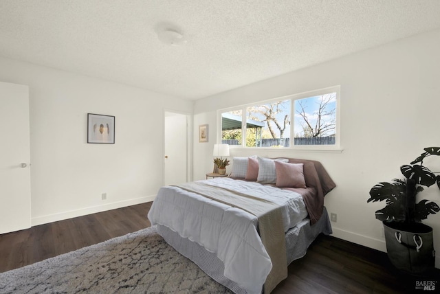 bedroom featuring a textured ceiling, baseboards, and wood finished floors