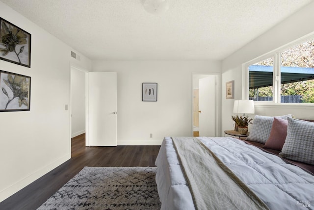 bedroom featuring visible vents, a textured ceiling, baseboards, and wood finished floors