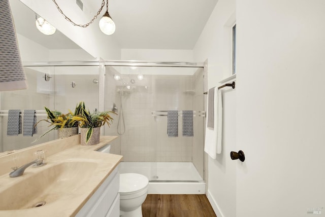 full bathroom featuring a stall shower, vanity, toilet, and wood finished floors