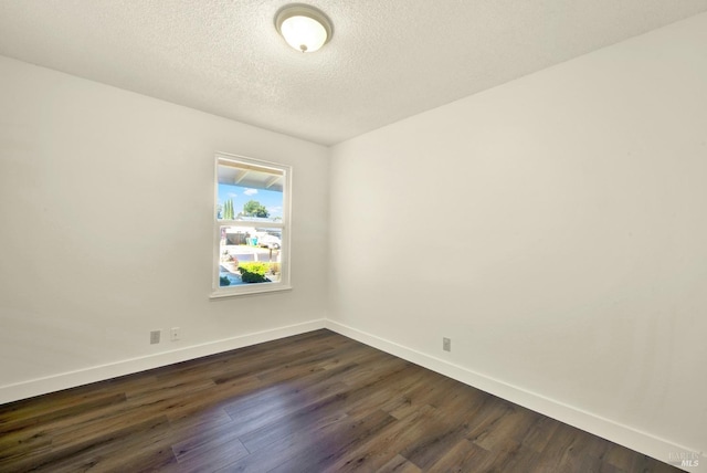 empty room featuring a textured ceiling, dark wood-type flooring, and baseboards