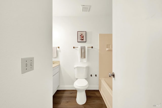 bathroom featuring baseboards, toilet, a bathing tub, wood finished floors, and vanity