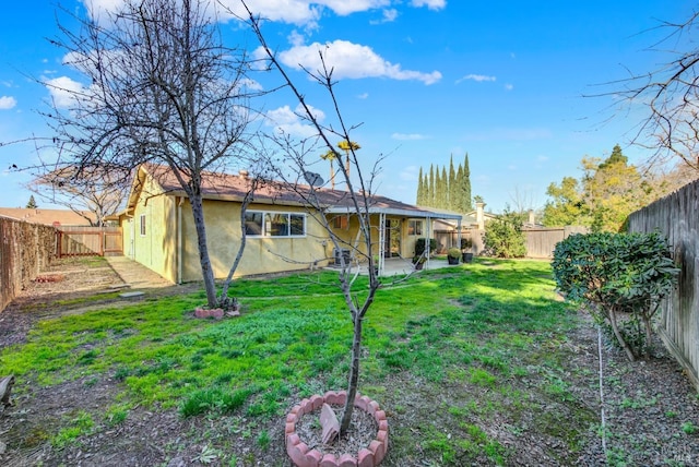 rear view of house with a fenced backyard, a patio, a lawn, and stucco siding