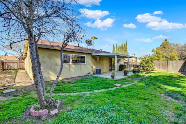 back of house with a fenced backyard, a yard, a patio area, central AC, and stucco siding