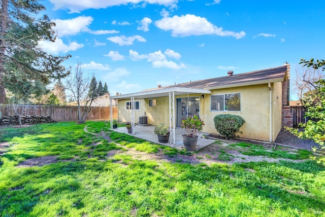 rear view of house featuring central AC unit, a patio, a fenced backyard, a yard, and stucco siding