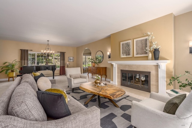 carpeted living room with a healthy amount of sunlight, arched walkways, a chandelier, and a tiled fireplace