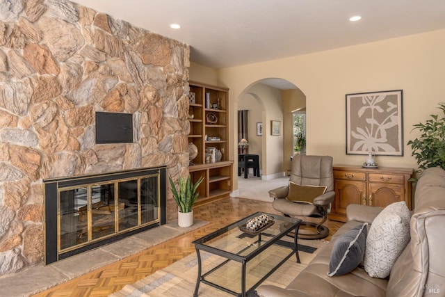 living area featuring arched walkways, a fireplace, baseboards, and recessed lighting