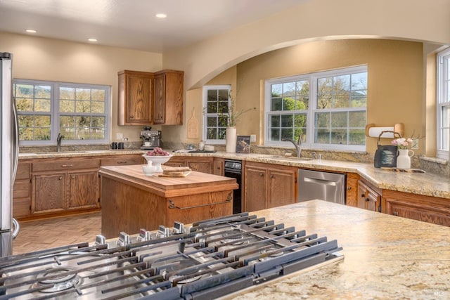 kitchen with brown cabinets, wooden counters, stainless steel appliances, and a sink