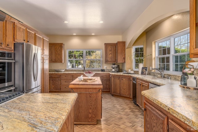 kitchen with brown cabinetry, freestanding refrigerator, a healthy amount of sunlight, and a kitchen island