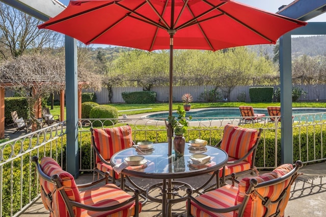 view of patio featuring outdoor dining area, a fenced backyard, and a fenced in pool