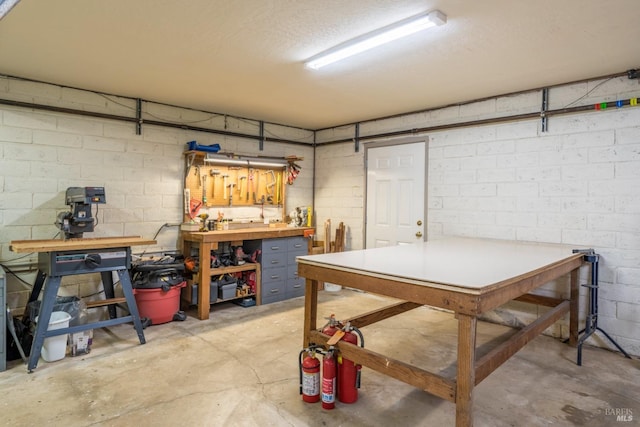 below grade area with a textured ceiling, a workshop area, and concrete block wall