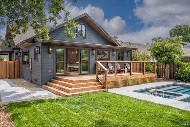 rear view of property featuring a yard, fence, a wooden deck, and a fenced in pool