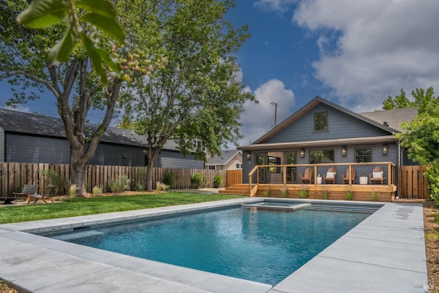 view of pool with a pool with connected hot tub, fence, a deck, and a lawn