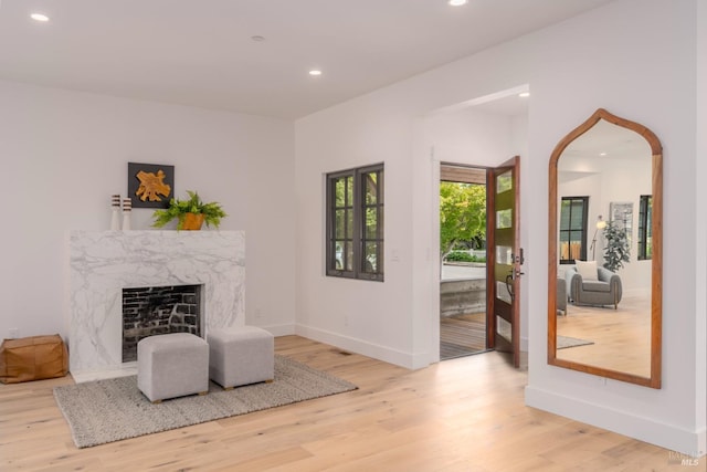 sitting room with light wood-style floors, a high end fireplace, baseboards, and recessed lighting