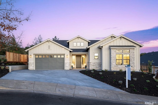 view of front of house featuring concrete driveway, an attached garage, board and batten siding, fence, and stone siding