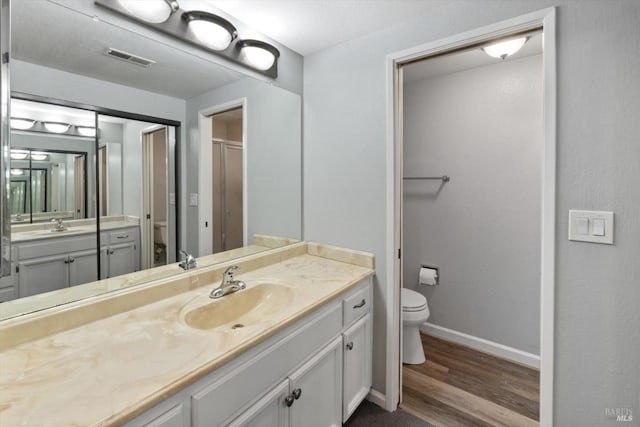 full bathroom featuring baseboards, visible vents, toilet, wood finished floors, and vanity