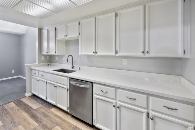 kitchen with stainless steel dishwasher, white cabinetry, a sink, and light wood finished floors