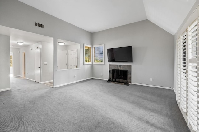 unfurnished living room with visible vents, lofted ceiling, baseboards, a tile fireplace, and carpet flooring
