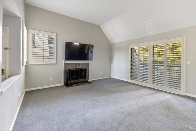 unfurnished living room featuring baseboards, carpet flooring, lofted ceiling, and a tile fireplace