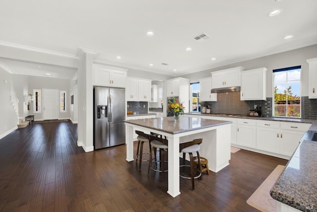 kitchen with appliances with stainless steel finishes, dark wood-type flooring, visible vents, and a center island