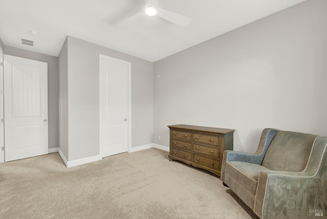 living area with baseboards, visible vents, ceiling fan, and light colored carpet