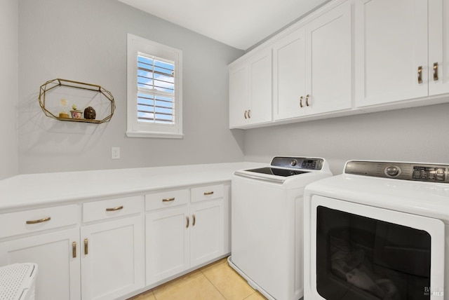 washroom featuring light tile patterned floors, washing machine and dryer, and cabinet space