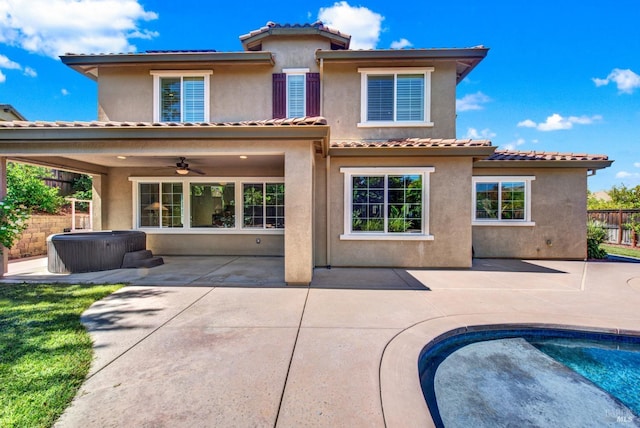 rear view of house with a patio area, a jacuzzi, and stucco siding