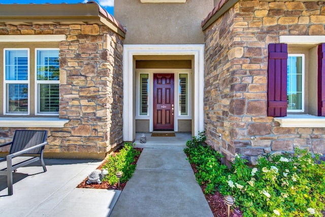 doorway to property featuring stone siding and stucco siding