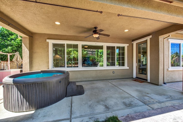 view of patio / terrace with a hot tub, fence, and a ceiling fan