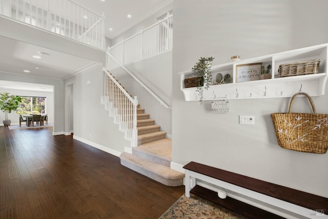 mudroom with ornamental molding, wood-type flooring, a towering ceiling, and baseboards