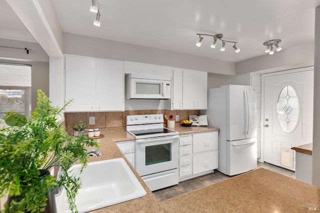 kitchen featuring white appliances, decorative backsplash, light countertops, white cabinetry, and a sink