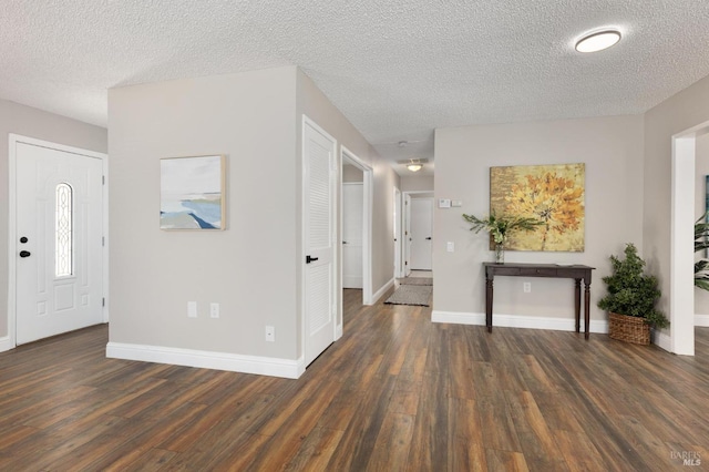 entrance foyer featuring a textured ceiling, baseboards, and wood finished floors