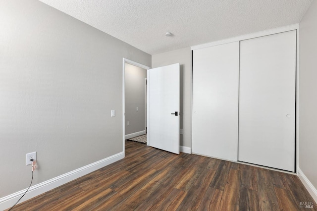 unfurnished bedroom with a closet, a textured ceiling, baseboards, and wood finished floors