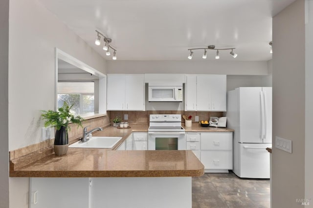 kitchen featuring white appliances, white cabinets, a peninsula, a sink, and backsplash