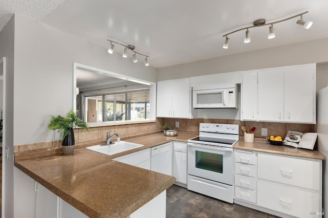 kitchen with a peninsula, white appliances, a sink, white cabinetry, and decorative backsplash