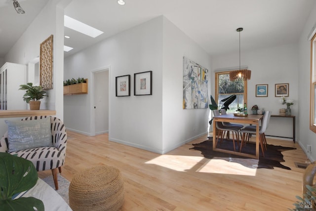 interior space with a skylight, baseboards, visible vents, wood finished floors, and an inviting chandelier