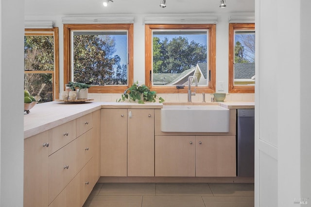 kitchen featuring dishwasher, light tile patterned floors, light countertops, and a sink