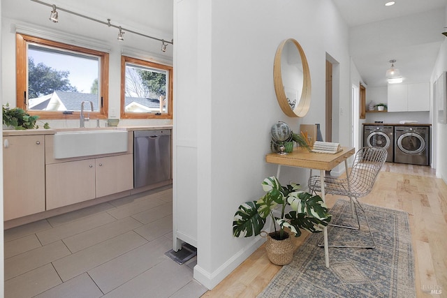 kitchen with dishwasher, independent washer and dryer, a sink, and light wood-style flooring