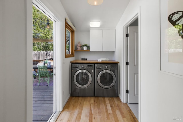 laundry room featuring light wood-style flooring, washing machine and dryer, and cabinet space