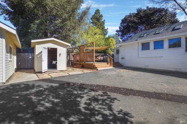 exterior space featuring an outbuilding, a patio, fence, a wooden deck, and a shed