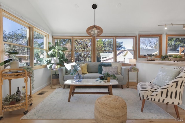 sunroom with lofted ceiling, a healthy amount of sunlight, and visible vents