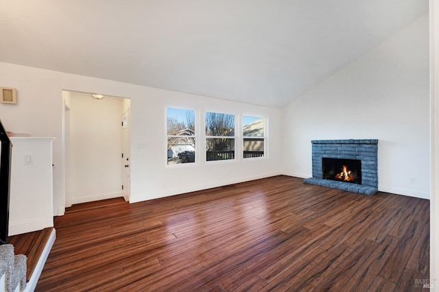 unfurnished living room with a lit fireplace, baseboards, vaulted ceiling, and wood finished floors