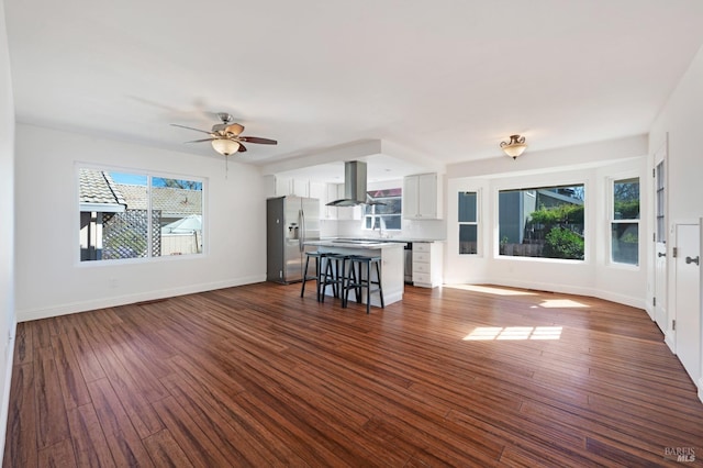 unfurnished living room with dark wood-style floors, a sink, baseboards, and a ceiling fan